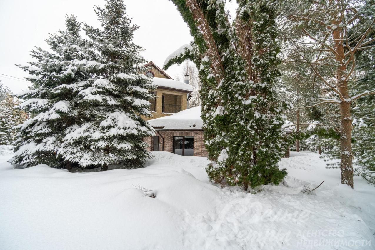 Дом стоит на живописном участке с хвойными деревьями, кустарниками, клумбами, газоном