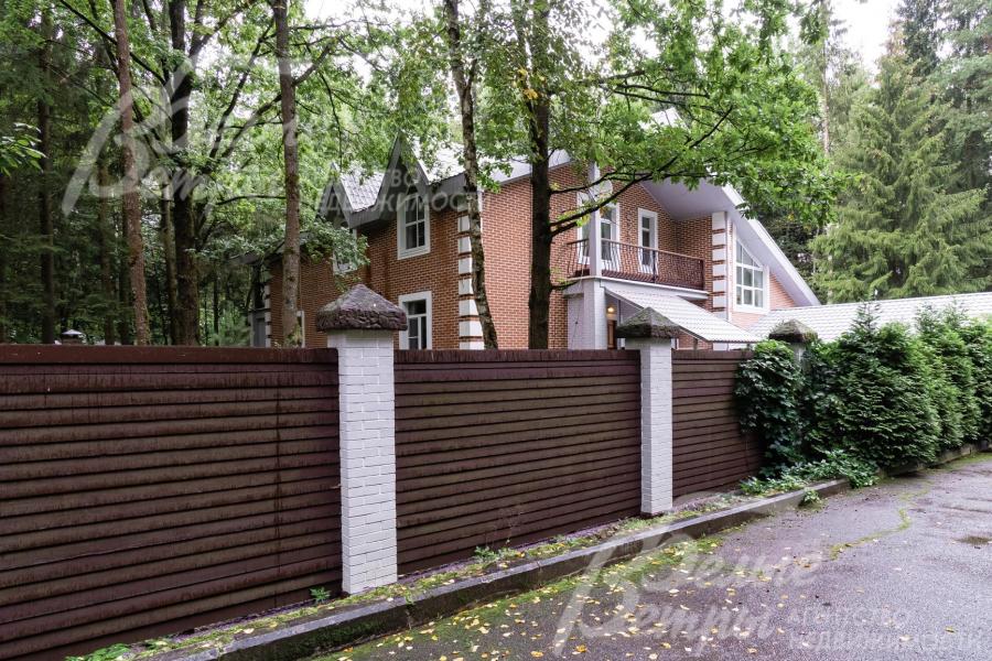 Участок со всех сторон огорожен высоким забором на кирпичных столбах