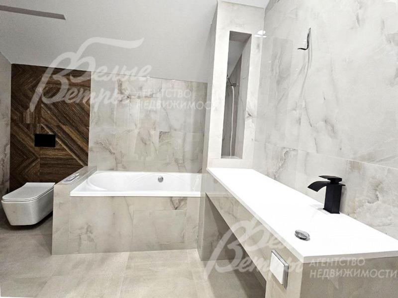 Санузел на втором этаже отделан керамогранитом "под белый мрамор", есть ванная и душевая