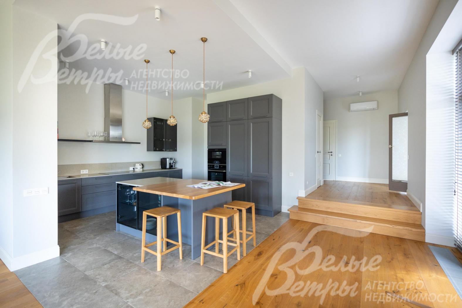 Кухня с гарнитуром и островом отделена от пространства гостиной-столовой контрастным полом и стенами без дверей