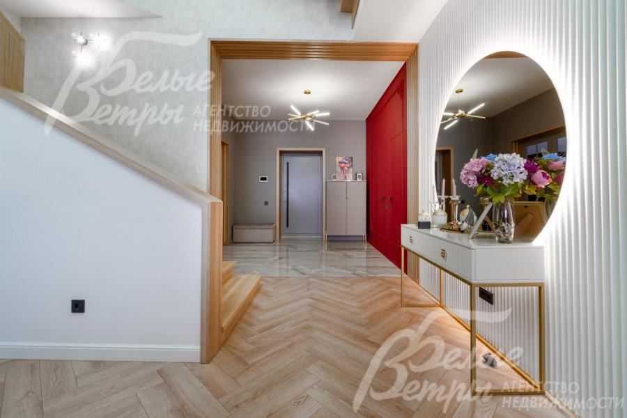 Напротив лестницы - круглое зеркало с консолью из МДФ. Портал отделан декоративными рейками из ясеня