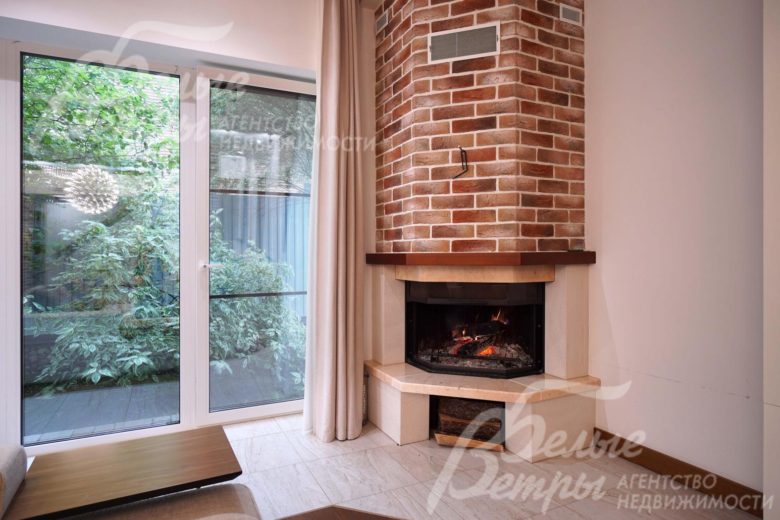 В гостиной установлен угловой дровяной камин с дымоходом, отделанным "под кирпич"