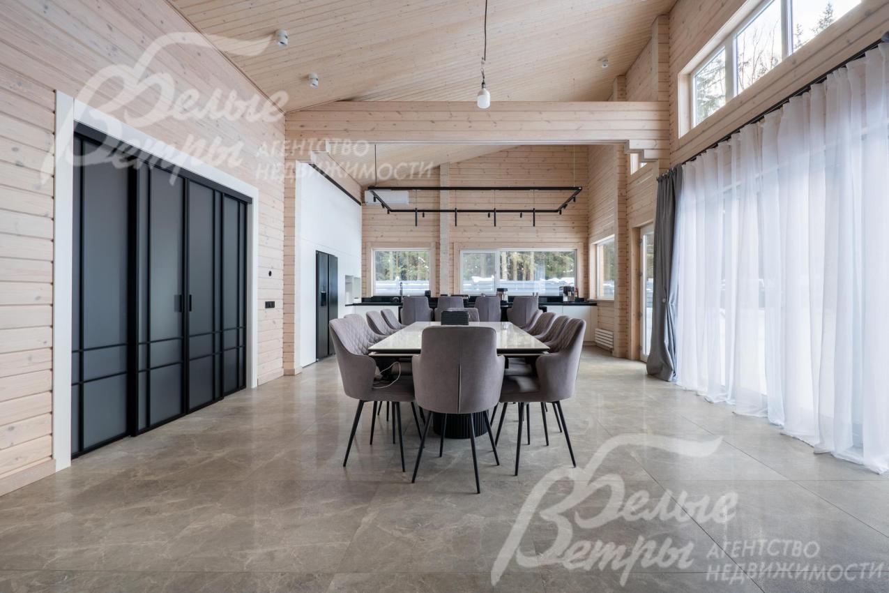 В зоне гостиной размещён большой обеденный стол, справа - выход на террасу через портал