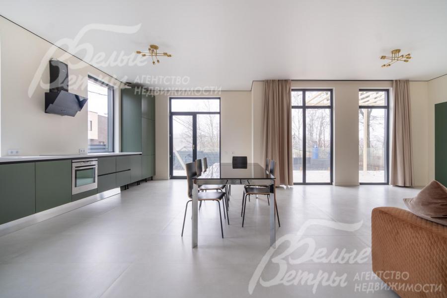 Зона кухни-столовой: установлен гарнитур глубокого оливкового цвета, столовая группа и диван