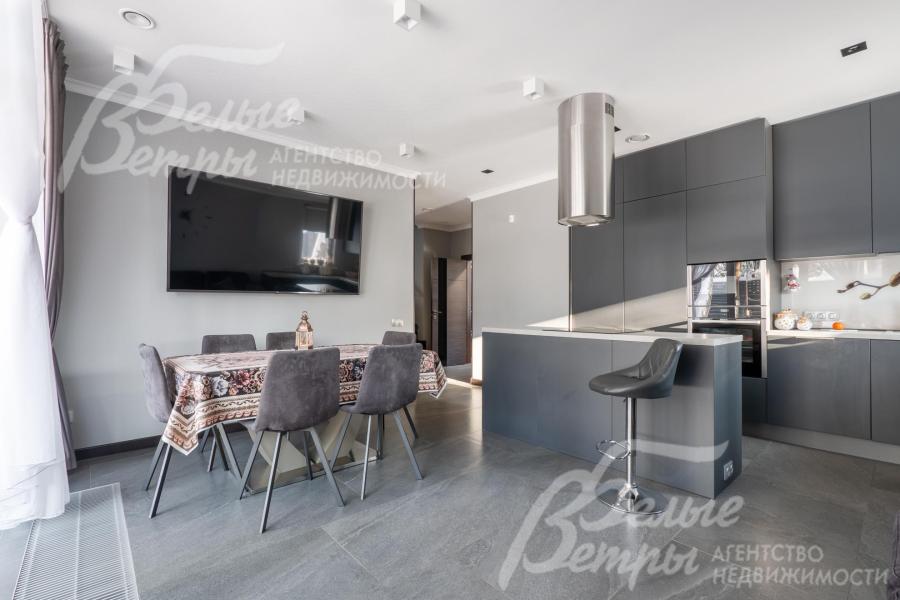 Интерьер кухни‑столовой выполнен в благородных бело‑серых оттенков, предусмотрена многоуровневая система освещения