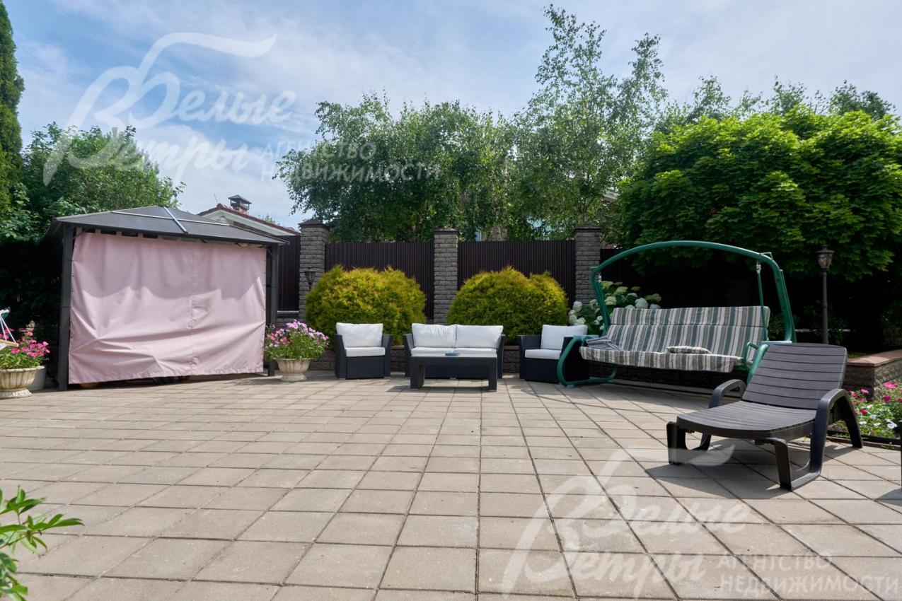 На участке установлены садовые качели, есть садовая мебель и беседка