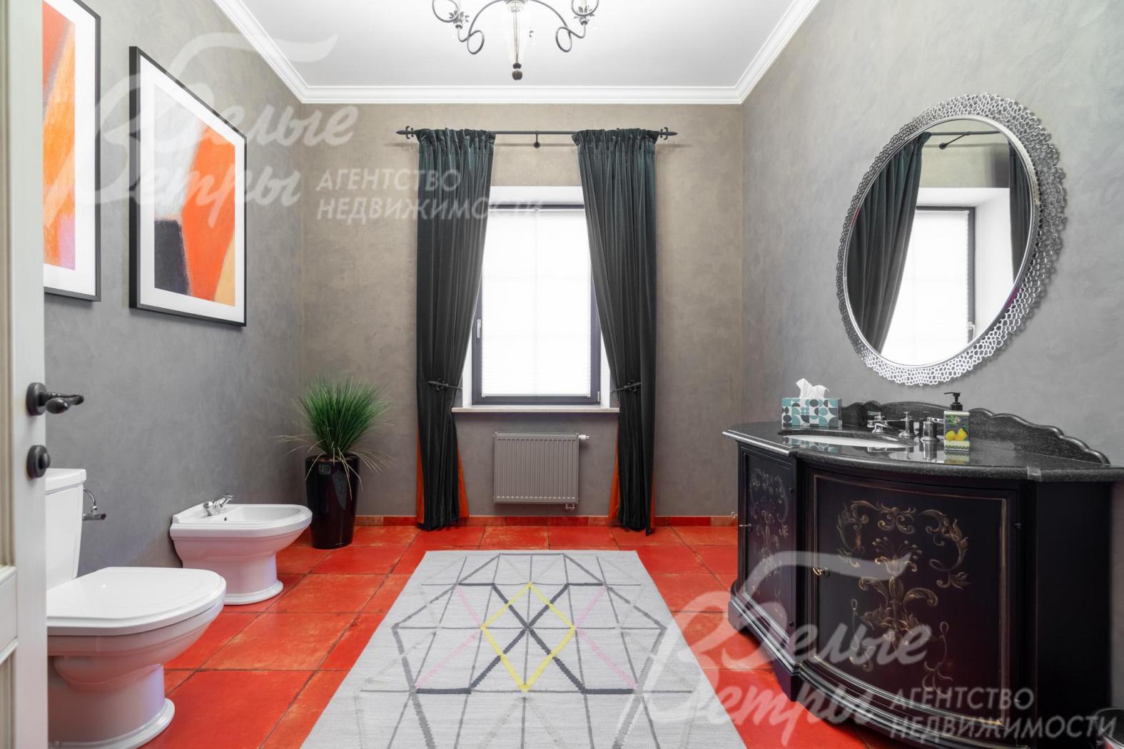 Санузел на первом этаже с насыщенным акцентным терракотово-красным полом, тумбой под раковину с изысканным орнаментом и картинами