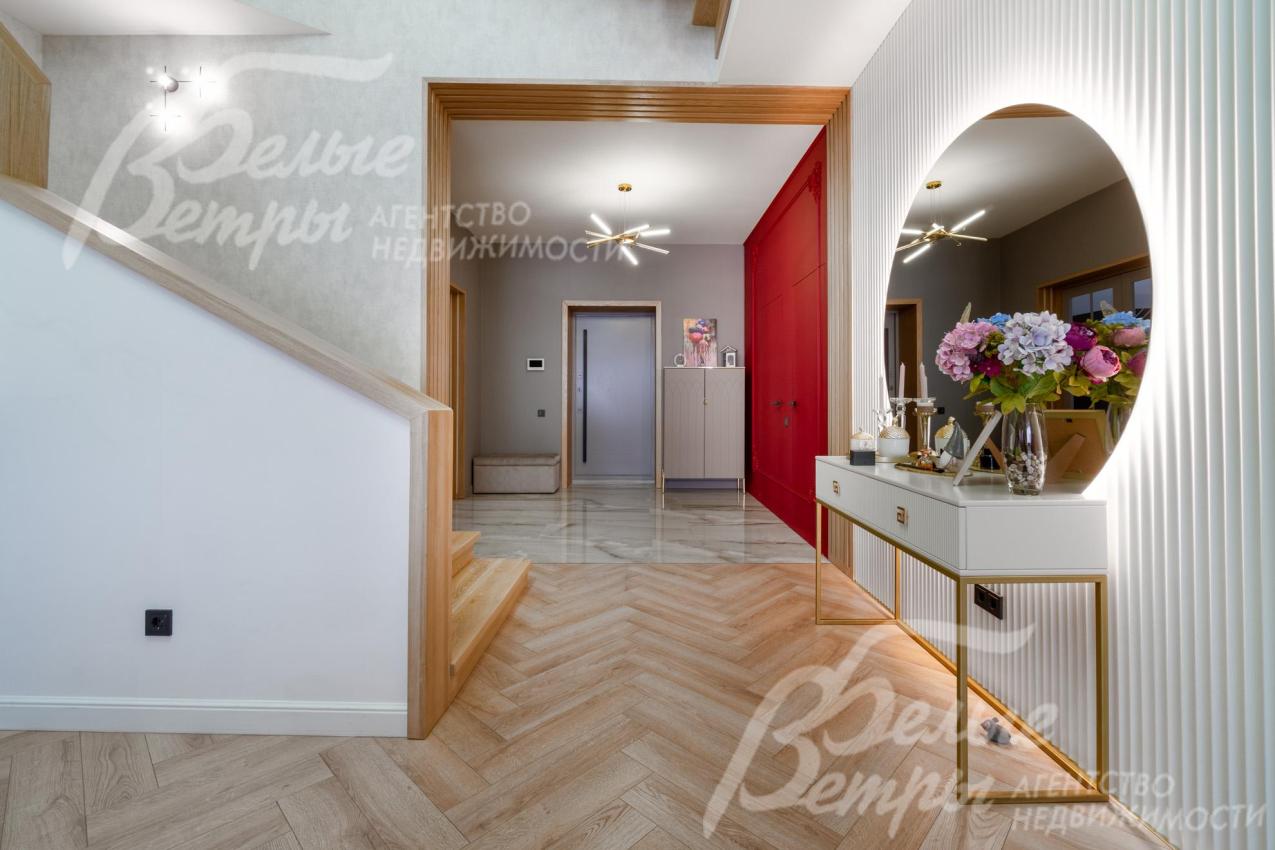 Напротив лестницы - круглое зеркало с консолью из МДФ. Портал отделан декоративными рейками из ясеня