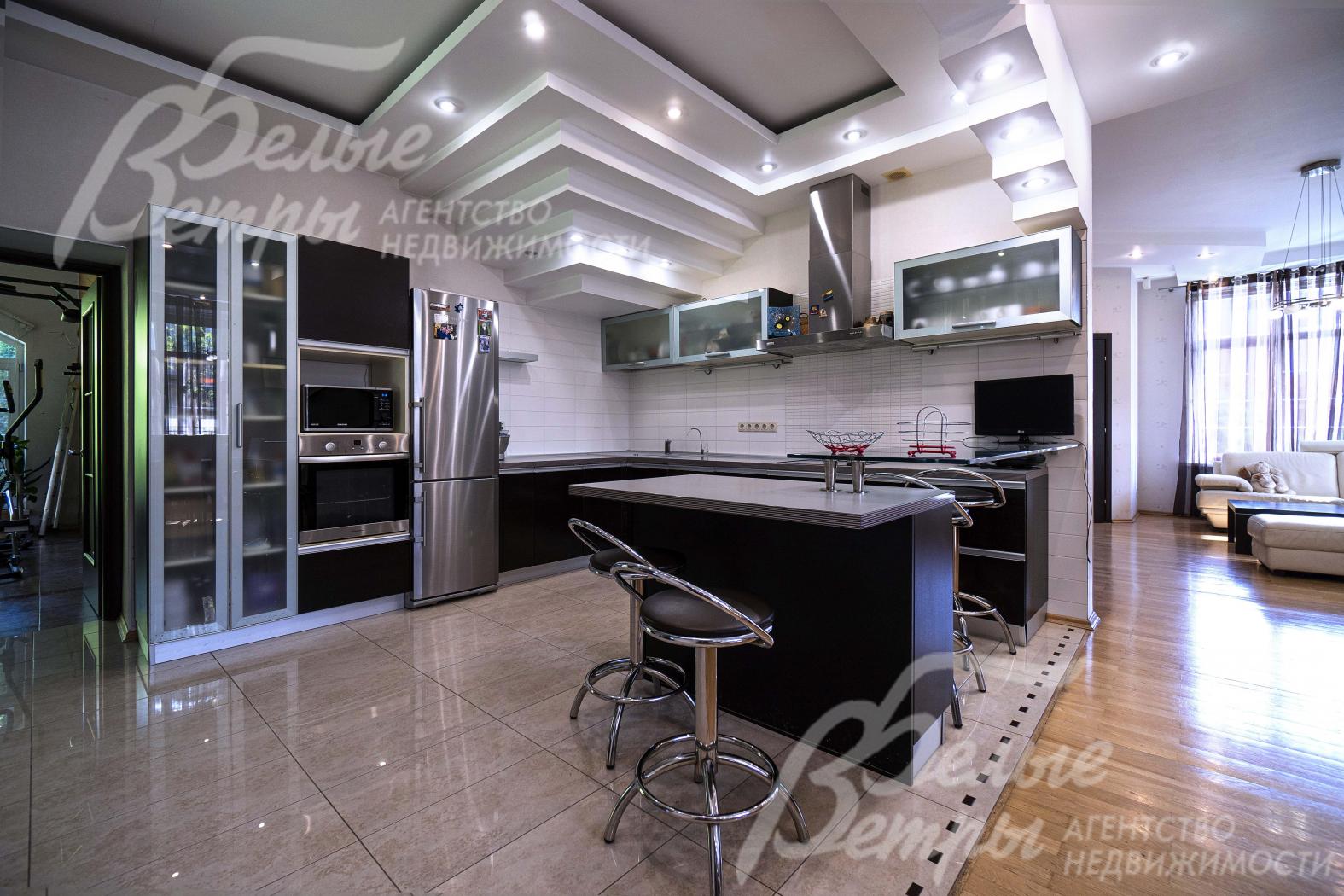 Кухня-столовая с разделением зон напольным покрытием и многоуровневыми потолками из гипсокартона