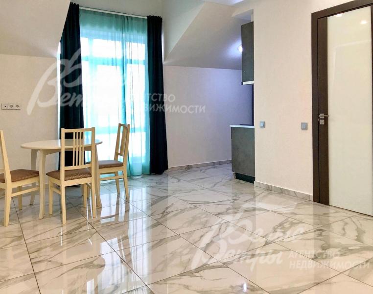 Кухня-столовая одной из студий. В доме - большие окна в пол, отделка в светло-серых тонах