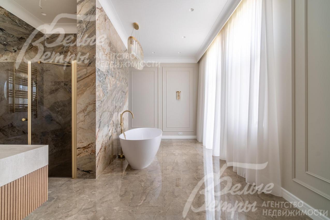 Ванна размещена за декоративной перегородкой напротив окна и балкона