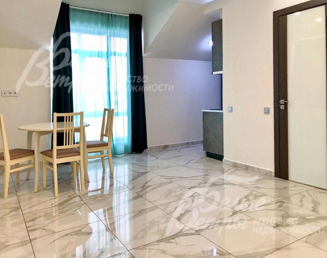 Кухня-столовая одной из студий. В доме - большие окна в пол, отделка в светло-серых тонах