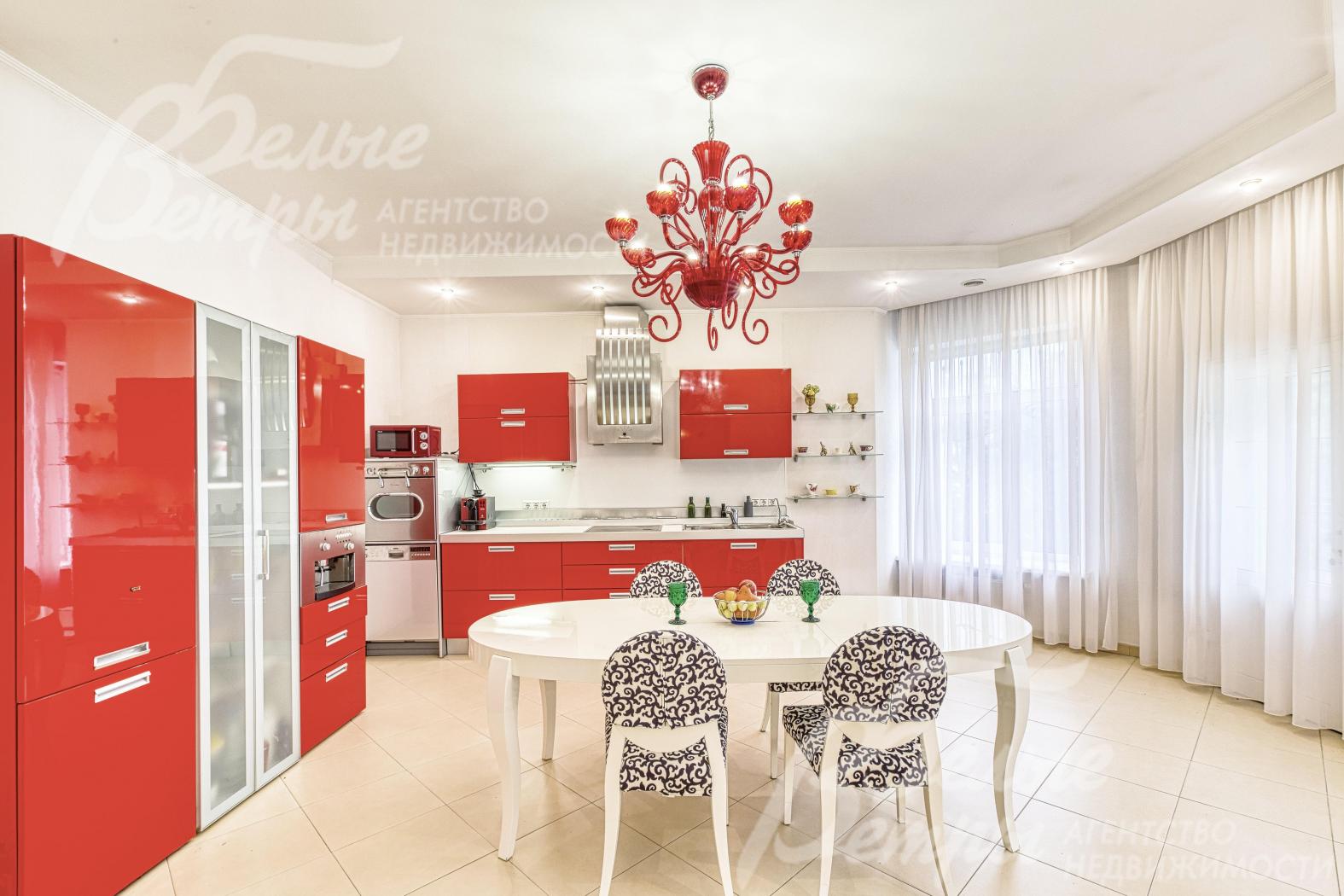 На кухне-столовой установлен контрастный гарнитур со встроенной бытовой техникой и обеденная группа