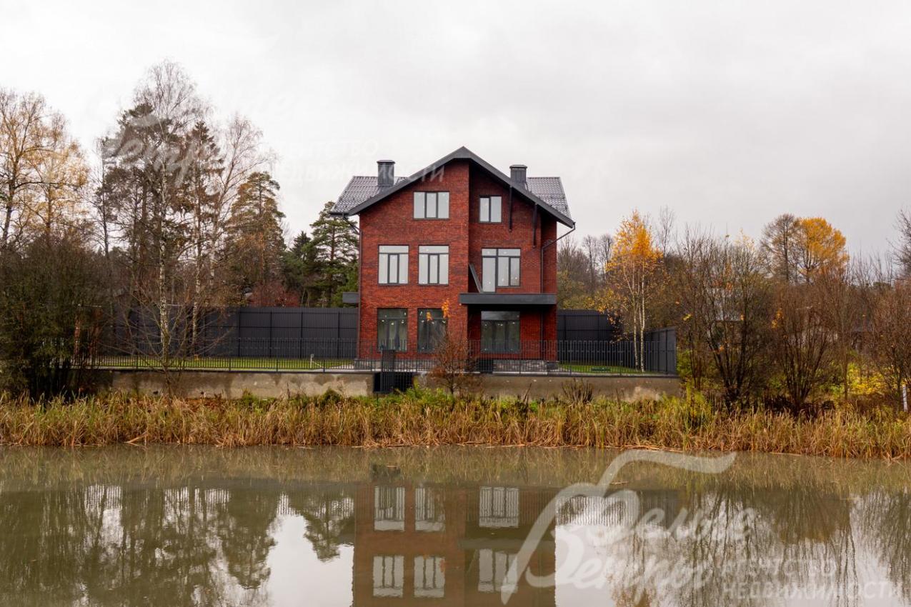 В зеркальной глади водоёма живописно отражается силуэт дома