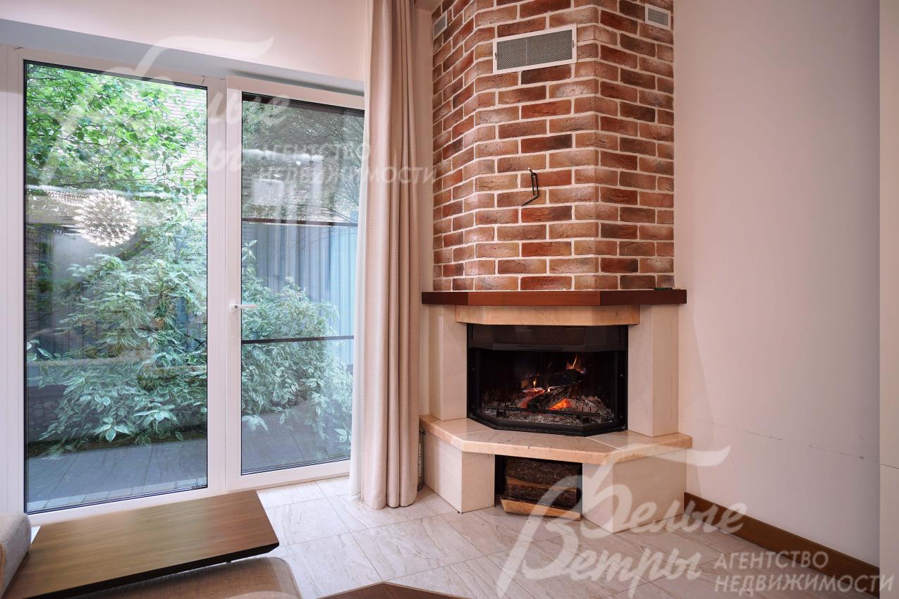 В гостиной установлен угловой дровяной камин с дымоходом, отделанным "под кирпич"