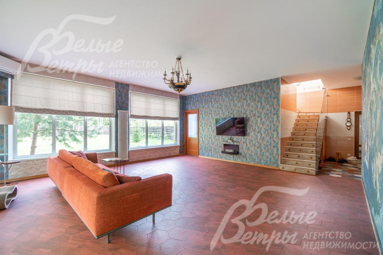 В гостиной выложена плитка и сделаны тёплые полы. На второй этаж ведёт монолитная лестница