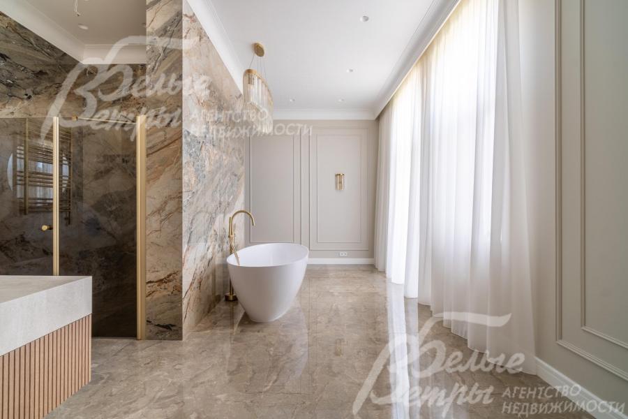 Ванна размещена за декоративной перегородкой напротив окна и балкона