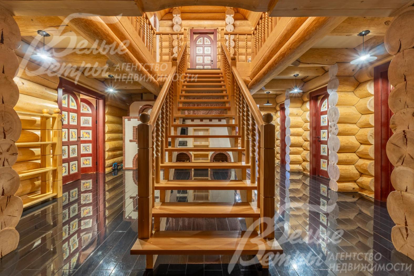Деревянная лестница на второй этаж словно сошла со страниц русской сказки: балясины, тёплые оттенки дерева и эффектная подсветка создают атмосферу волшебного терема