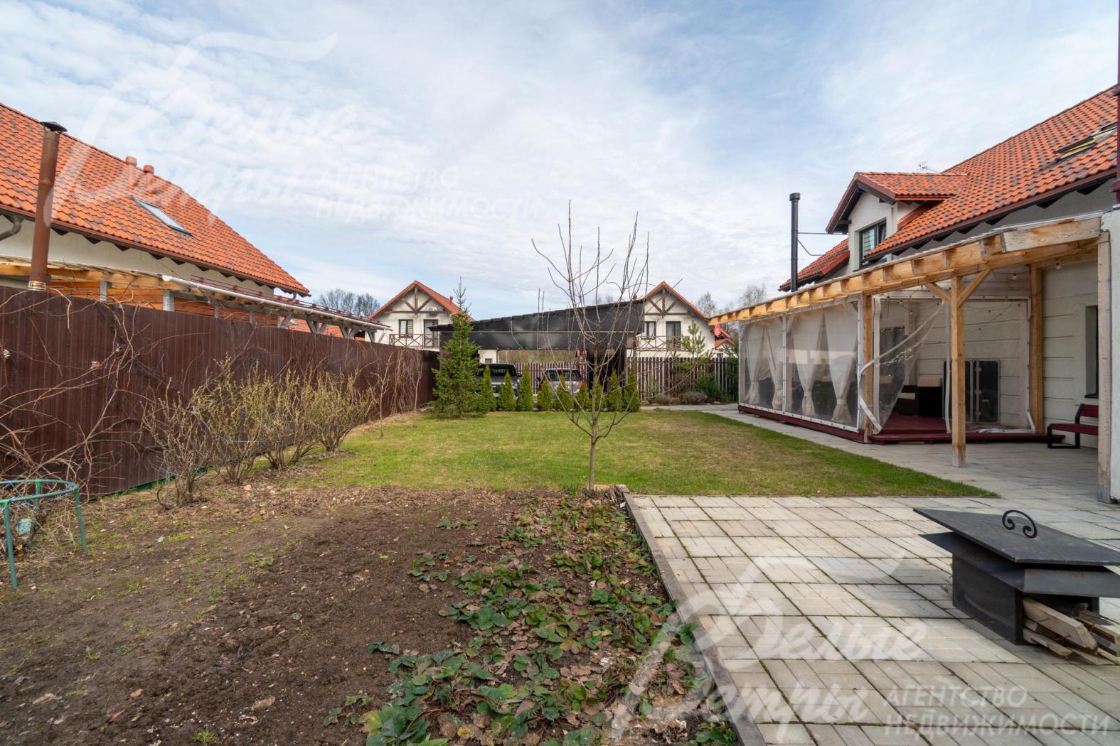 К террасе примыкает мощёная площадка, выложенная крупной светлой плиткой. На площадке стоит мангал