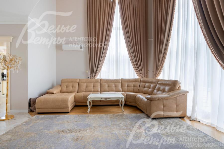 Гостиная - двухсветная, с окнами от пола до потолка и удобным большим диваном