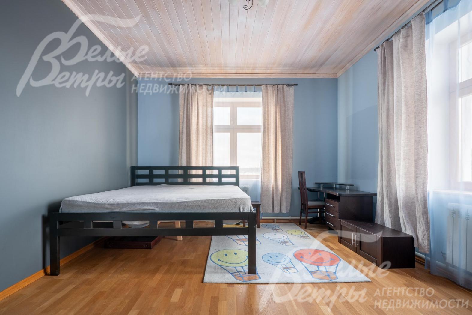 Одна из спален на втором этаже с кроватью и рабочим местом