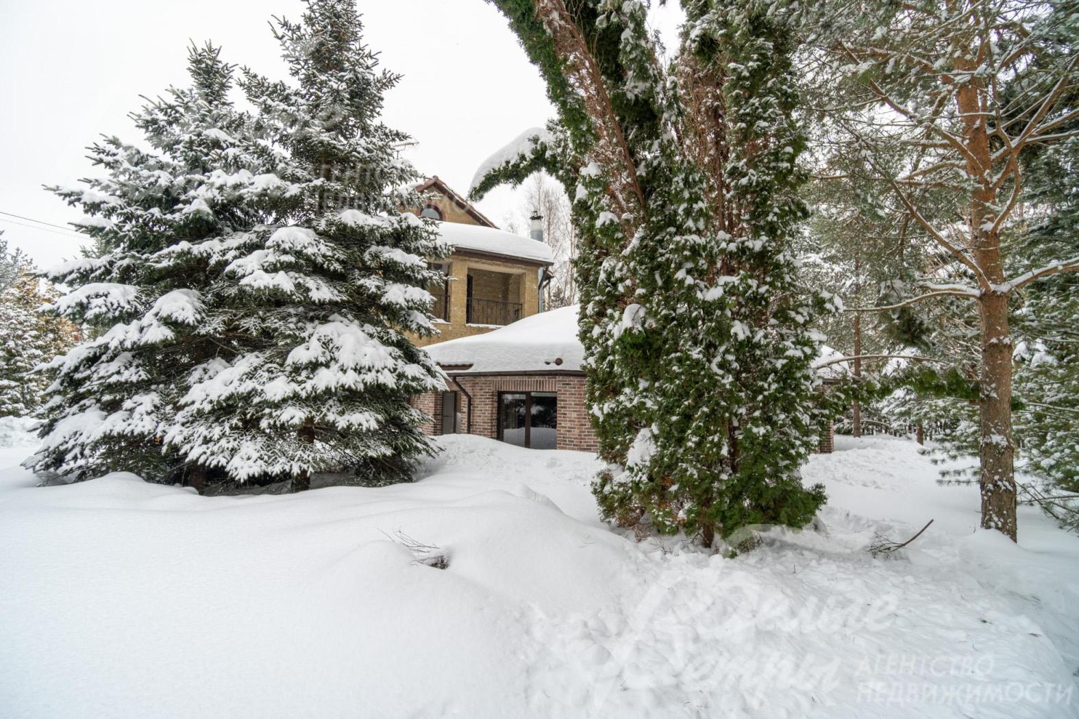 Дом стоит на живописном участке с хвойными деревьями, кустарниками, клумбами, газоном
