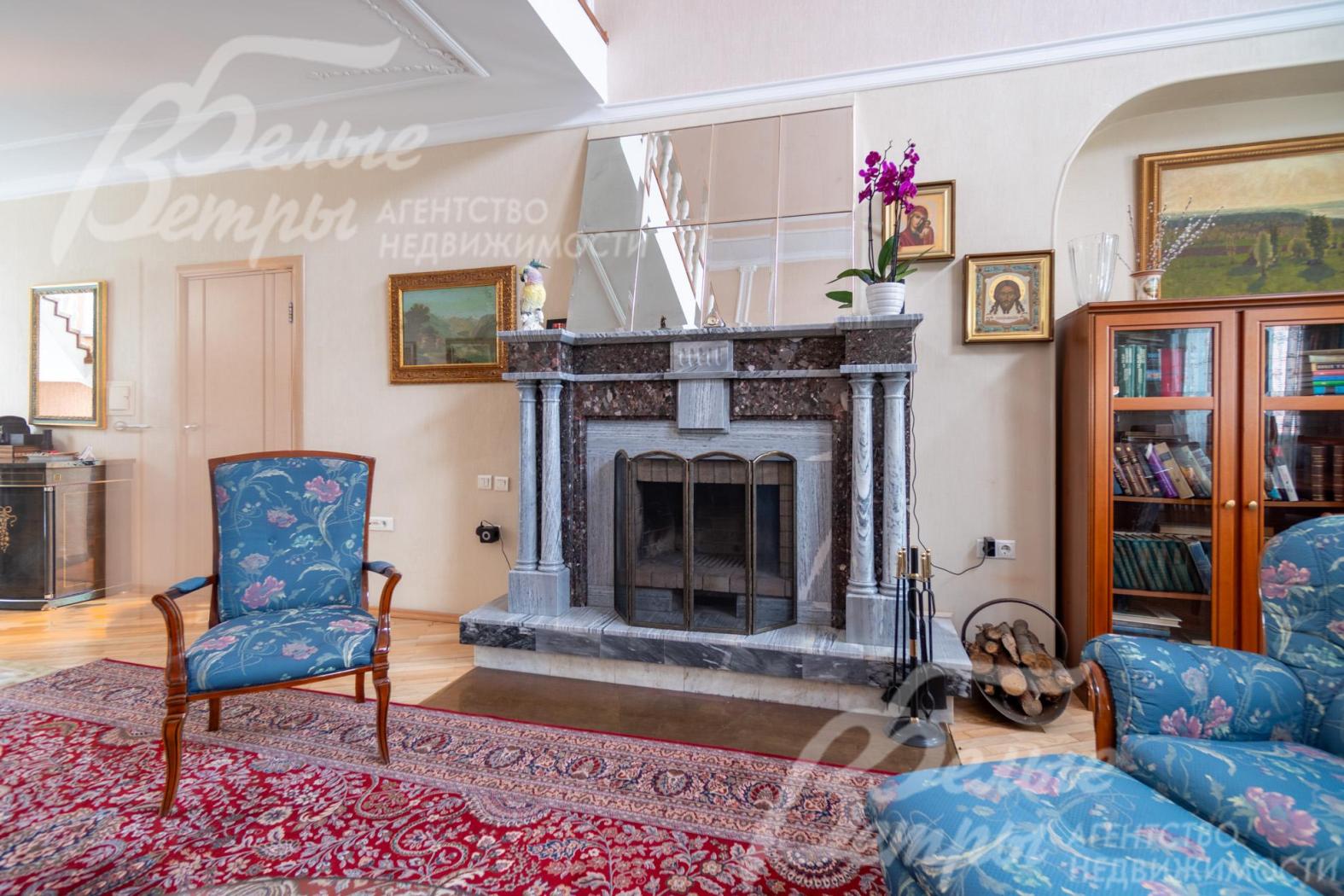 Гостиную украшает большой камин в классическом стиле с порталом, отделанным мрамором серо-серебристого оттенка