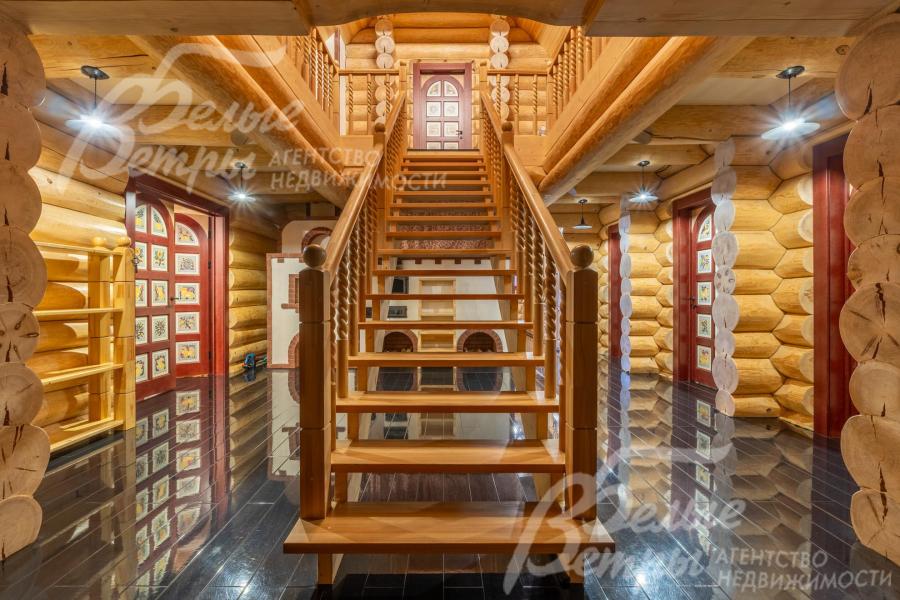 Деревянная лестница на второй этаж словно сошла со страниц русской сказки: балясины, тёплые оттенки дерева и эффектная подсветка создают атмосферу волшебного терема
