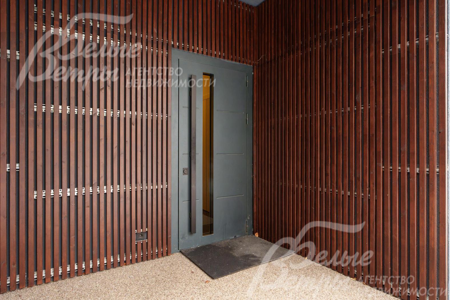 Вход в дом. Дверь с электронной защелкой. В отделке фасада использован деревянный брусок