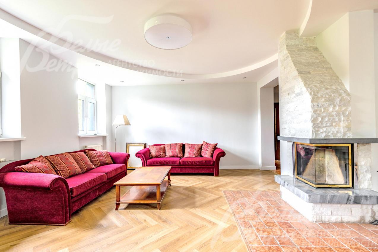 Гостиную украшает камин с двусторонним порталом, отделанным белым кварцем и серым мрамором