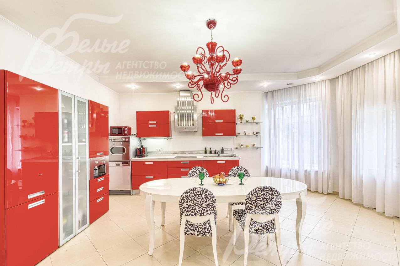 На кухне-столовой установлен контрастный гарнитур со встроенной бытовой техникой и обеденная группа