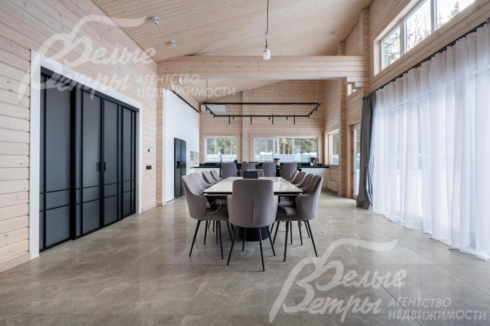 В зоне гостиной размещён большой обеденный стол, справа - выход на террасу через портал