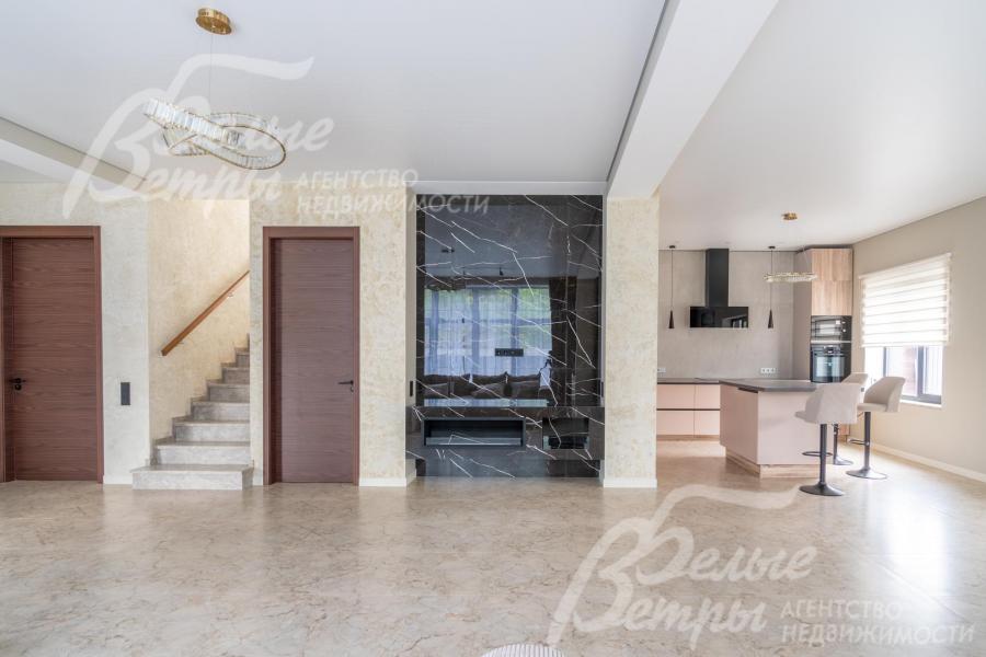 Стены зоны кухни-столовой-гостиной окрашены в светлый цвет, установлены высокие контрастные двери