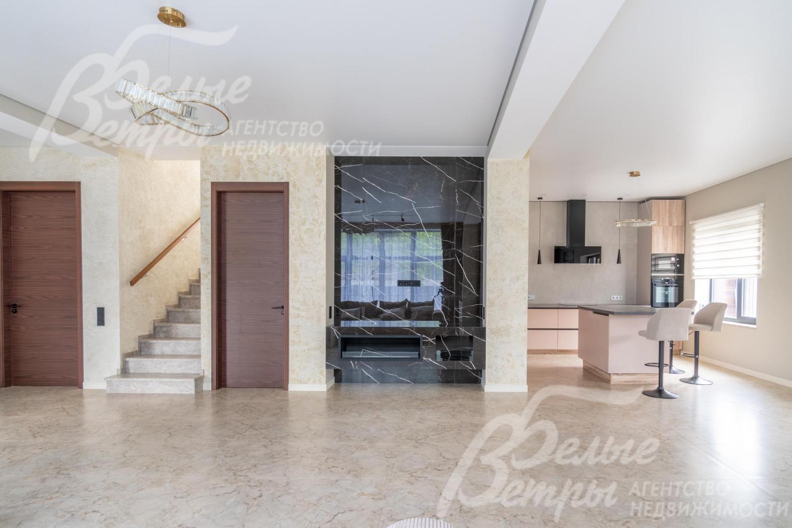 Стены зоны кухни-столовой-гостиной окрашены в светлый цвет, установлены высокие контрастные двери